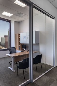 an office cubicle with glass walls and black chairs