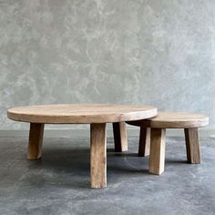 two wooden benches sitting next to each other on cement floored area with concrete wall in background