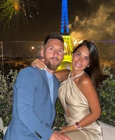 a man and woman pose for a photo in front of the eiffel tower