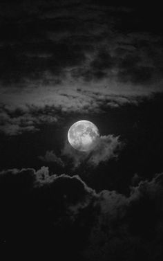 the full moon is seen through clouds in black and white