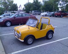 an old yellow car parked in a parking lot