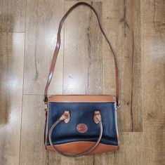 Featuring a classic vintage Dooney and Bourke navy and tan leather crossbody handbag. This is a perfect everyday bag style that you can wear as a crossbody bag or a handbag. It's in a wonderful navy color with a rich tan trimming throughout. The crossbody strap is removable. It has one large outside pocket and two large inside pockets. The two inside pockets are one pocket being a zippered pocket and the other being a more open pocket. Top zipper closure with Dooney and Bourke zipper. The overal Vintage Dooney And Bourke, Minimalist Gifts, Leather Handbags Crossbody, Classic Casual, Dooney And Bourke, Navy Leather, Pocket Top, Bag Style, Dooney & Bourke