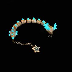 a bracelet with blue beads and a star charm on it's end, against a black background