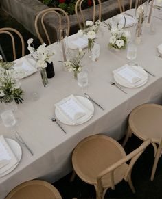 the table is set with white flowers and place settings