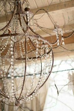 a chandelier with beads hanging from it's ceiling in front of a window