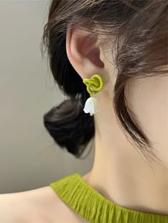 a woman wearing green and white earrings