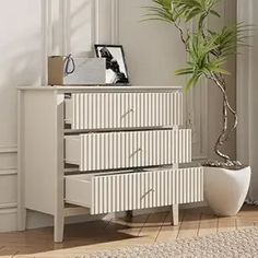 a white chest of drawers sitting next to a potted plant