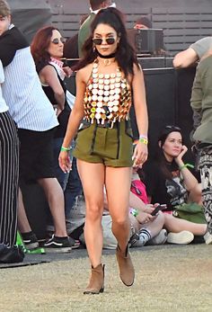 a woman is walking on the grass in front of some people at an outdoor concert