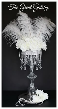 a vase with white flowers and feathers on it