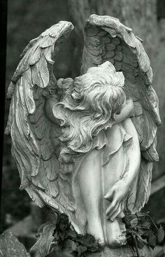 an angel statue sitting on top of a grave