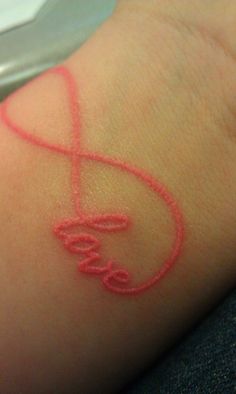 an image of someone's wrist with the word love drawn in red on it