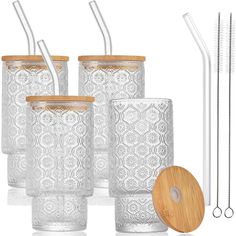 six glass tumblers with wooden lids and metal straws in front of each other