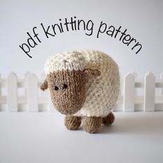 a knitted sheep is standing in front of a white fence