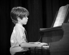 a young boy is playing the piano in black and white