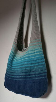 a blue and gray bag hanging from a hook on a wall next to a white wall