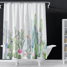 a white bath tub sitting next to a shower curtain with cactus designs on the side