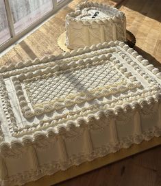 two white cakes sitting on top of a wooden table next to each other in front of a window