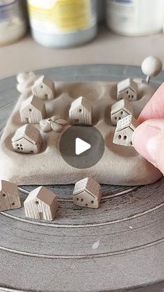 a person is playing with clay houses on a table