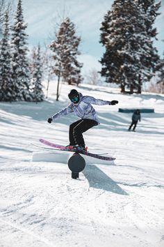 a person on skis jumping over a rail in the snow with trees behind them