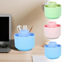 a laptop computer sitting on top of a desk next to cups and utensils