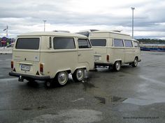 two vans parked in a parking lot with cloudy skies behind them and one van is off to the side