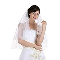 a woman in a white dress and veil posing for the camera with her hand on her shoulder