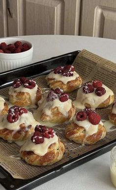 there are many croissants on the tray with raspberries and cream