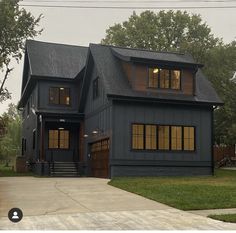 a black house with two story windows and dark shingles