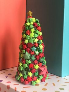 a small christmas tree made out of bows on top of a gift box next to a colorful wall