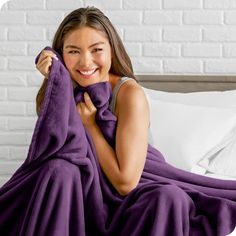 a smiling woman wrapped in a purple blanket