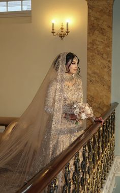 a woman in a wedding dress is standing on the stairs with her veil over her head