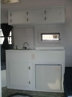 a kitchen with white cabinets and cupboards on the wall next to a sink area