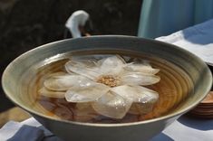 a bowl filled with water sitting on top of a table next to a white bird