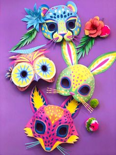 three masks with different designs on them sitting on a purple surface next to an orange flower