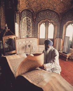 a man sitting on the floor with an open book in front of him and looking at it