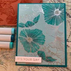 a close up of a card on a table with three markers and some papers next to it