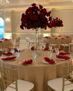 a table is set with red flowers and place settings