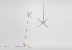 two white and gold objects hanging in the air with wires attached to each other, on a white background