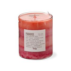 a candle with a label on it sitting in front of a white background that says paradise