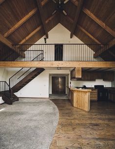 an empty living room with wood floors and ceiling fan in the center, stairs leading up to the second floor