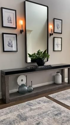 a mirror and some vases on a table in front of a wall with pictures