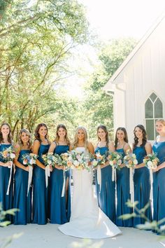 a group of bridesmaids in blue dresses holding bouquets