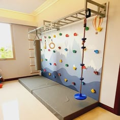 a child's play area with climbing ropes and toys on the wall, in front of a window