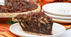 a piece of chocolate pecan pie on a plate with another slice in the background