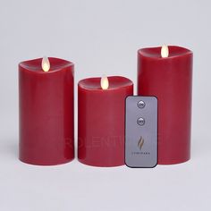 three red candles sitting next to each other with a remote control in front of them