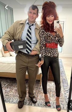 a man standing next to a woman taking a selfie in front of a mirror