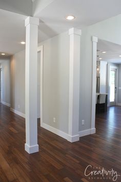 an empty living room with wood floors and white columns