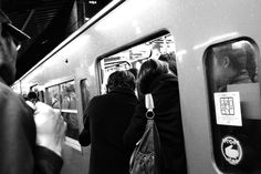 people standing on the side of a subway train