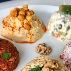 four different types of food on a plate with sauces and nuts around them,