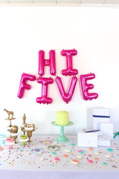 the table is covered with pink balloons and confetti, including one that says hit five